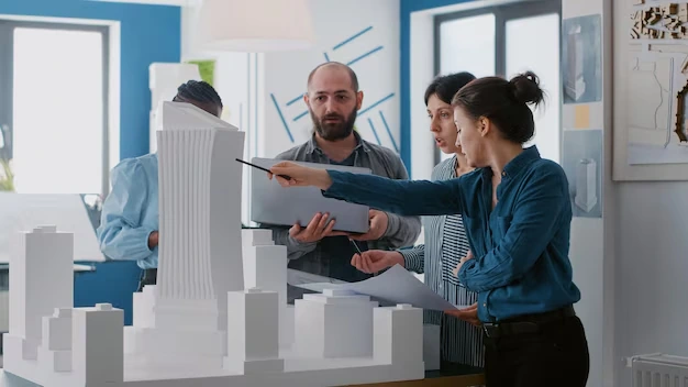 Multi ethnic people working with laptop tablet building model architecture project coworkers doing teamwork design maquette construction layout with blueprints 38871